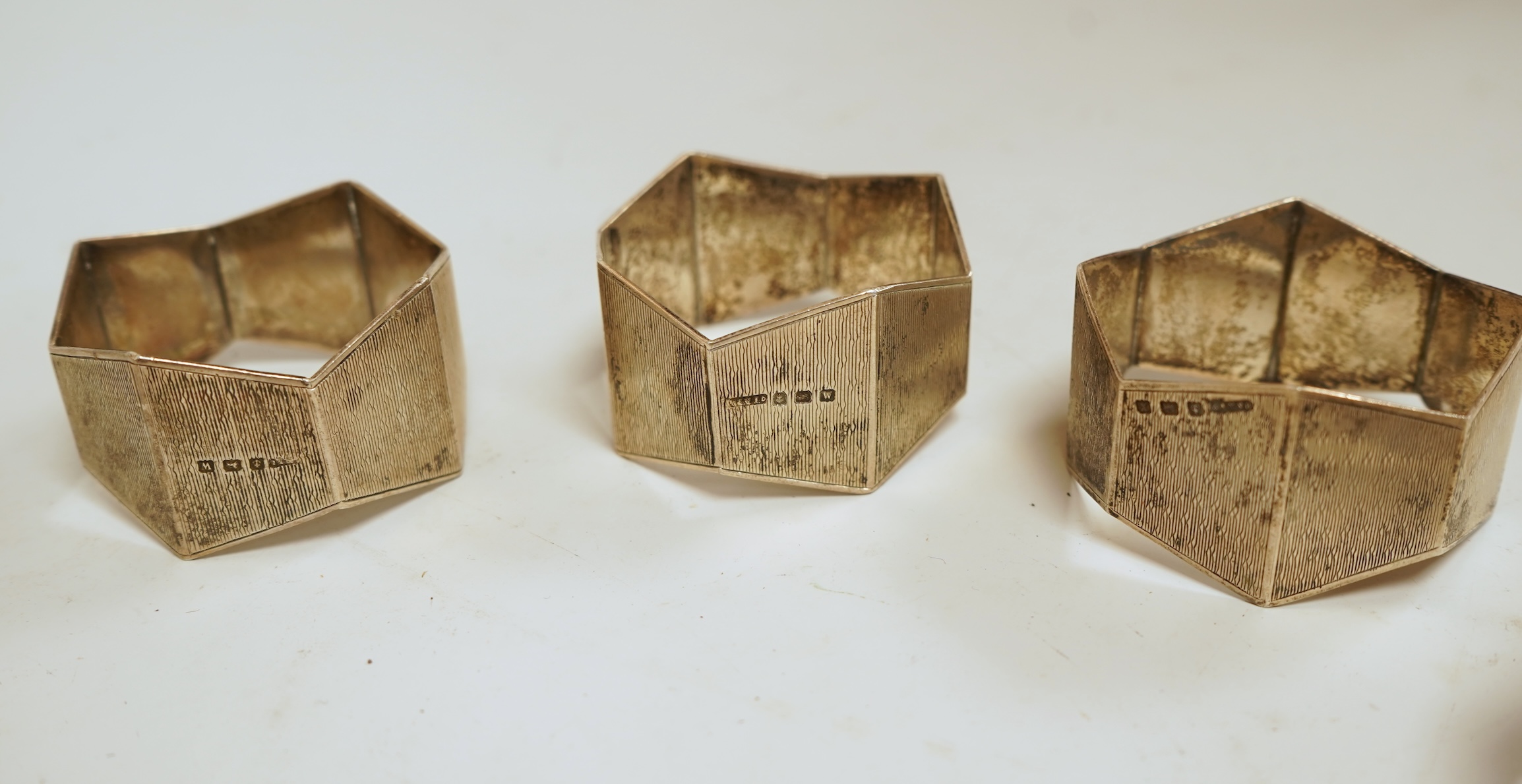 A small silver mounted capstan inkwell, a set of four George V engine turned silver napkin rings and a silver handled magnifying glass.
